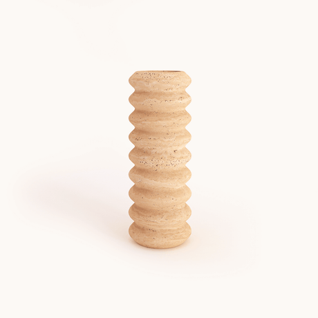 The Natural Beauty Oval Travertine Vase by Travertable is a tall, beige ceramic vase featuring a textured, wavy pattern against a light background. Its subtly speckled surface enhances its natural esthetic.