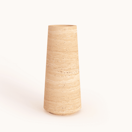 The Classic Beige Travertine Vase by Travertable stands on a neutral background, featuring a tall, cylindrical shape. Its speckled surface and earthy tan hue convey a minimalist, natural beauty.