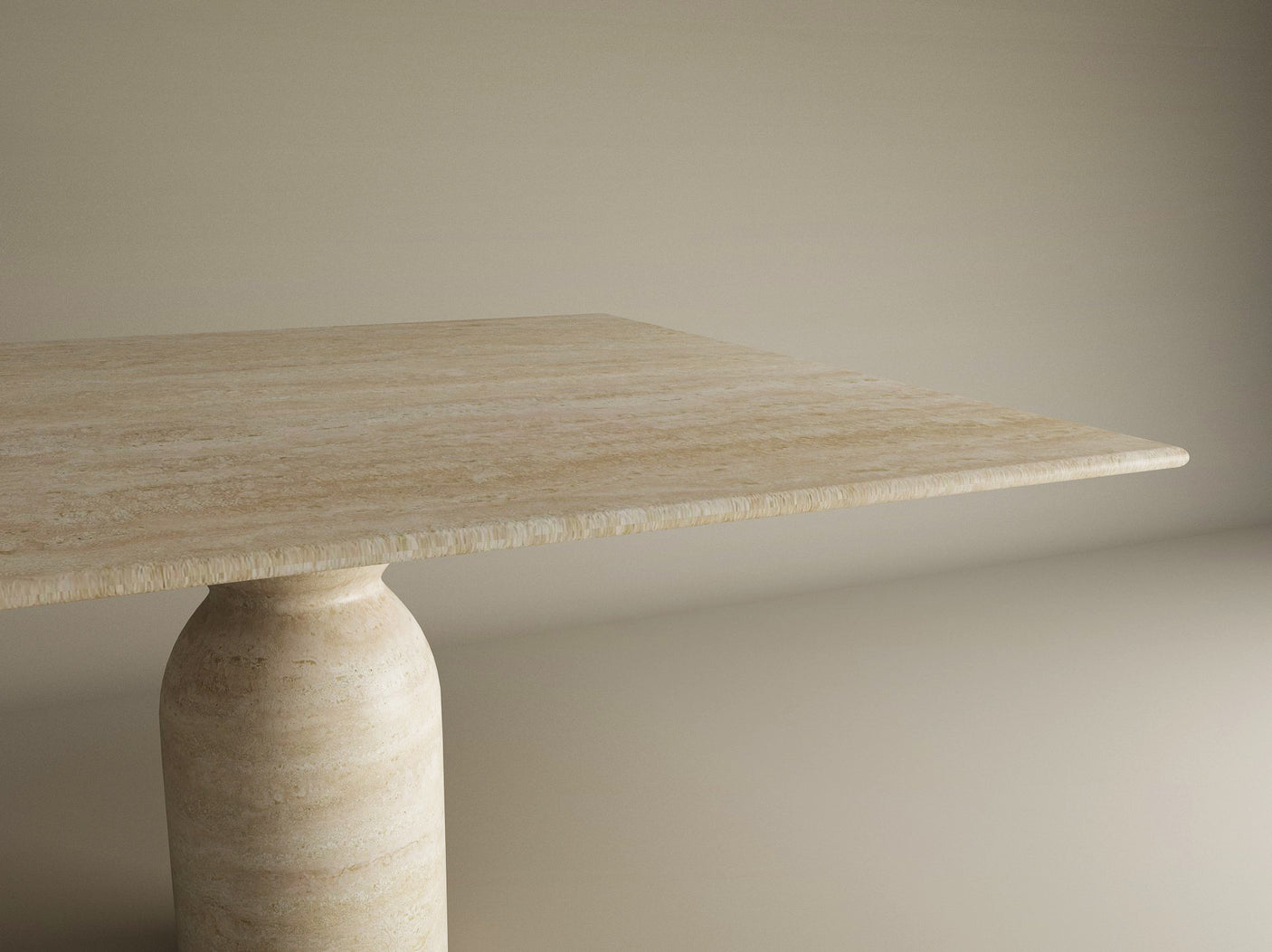 The TRAVERTABLE Square Travertine Dining Table features a smooth, light beige stone top and a sculptural round center base, shown partially against a neutral background to highlight its organic, timeless design. Customizable for your dining space.