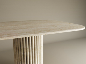 The TRAVERTABLE Rectangular Travertine Dining Table features a light beige stone top with rounded corners and a single cylindrical base with vertical grooves. This customizable table combines organic beauty and modern design. Neutral background.