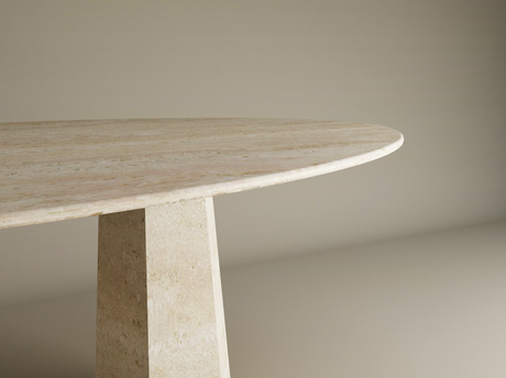 A close-up shows the TRAVERTABLE Ellips Travertine Dining Table with a beige, oval travertine tabletop and a solid, tapered round stone base against a plain, light background. Table is customizable.
