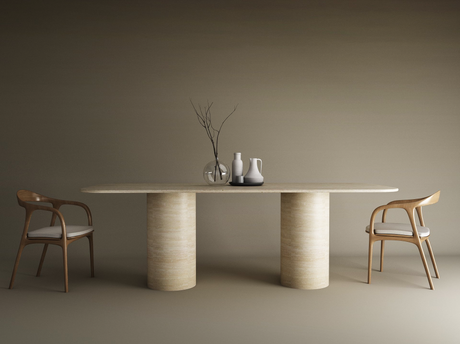 A minimalist dining area features the TRAVERTABLE Rectangular Travertine Dining Table with a smooth cylinder base, two wooden chairs with white cushions, and decorative vases with bare branches atop, all set against a neutral backdrop.