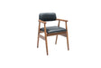 Travertables Executive Elegance Armchair features a minimalist modern design with ergonomic armrests, a wooden frame with slender legs, and black faux leather cushions for the seat and backrest. Its simple, angular charm is accentuated by the white background.